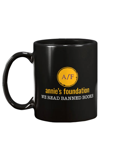 15 oz black mug featuring the yellow version of the Annie's Foundation logo and we read banned books